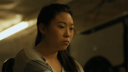 A Close Up Of A Woman 'S Face With A Purse Around Her Neck GIF