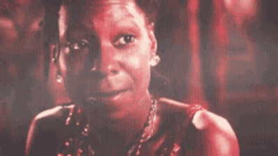A Close Up Of A Woman 'S Face With A Red Background And A Necklace . GIF
