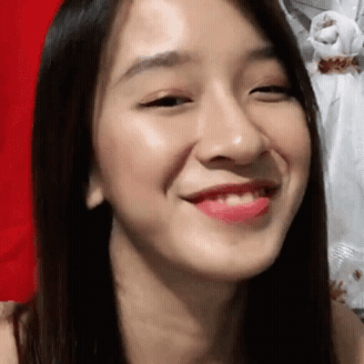 A Close Up Of A Woman 'S Face With A Red Background And A Smile On Her Face . GIF