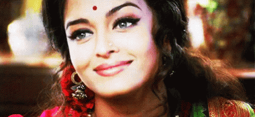 A Close Up Of A Woman 'S Face With A Red Dot On Her Forehead And Smiling . GIF