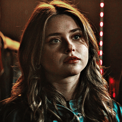 A Close Up Of A Woman 'S Face With A Red Light In The Background GIF