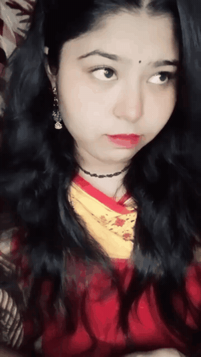 A Close Up Of A Woman 'S Face With A Red Shirt And Yellow Scarf GIF