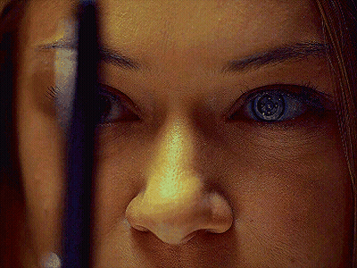 A Close Up Of A Woman 'S Face With A Reflection Of Herself In The Mirror GIF
