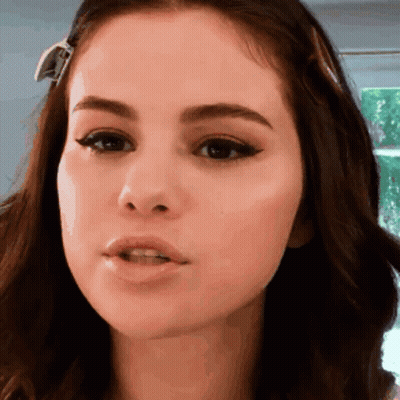 A Close Up Of A Woman 'S Face With A Ribbon In Her Hair GIF