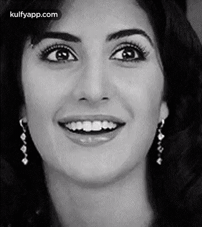 A Close Up Of A Woman 'S Face With A Smile And Earrings . GIF