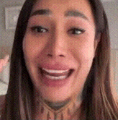 A Close Up Of A Woman 'S Face With A Smile On Her Face And A Tattoo On Her Neck . GIF