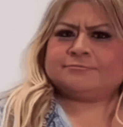 A Close Up Of A Woman 'S Face With A Smirk On Her Face . GIF