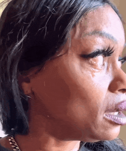 A Close Up Of A Woman 'S Face With A Tear On Her Eye . GIF
