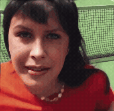 A Close Up Of A Woman 'S Face With A Tennis Net Behind Her GIF