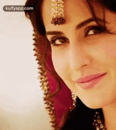 A Close Up Of A Woman 'S Face With A Veil On Her Head And A Smile On Her Face . GIF