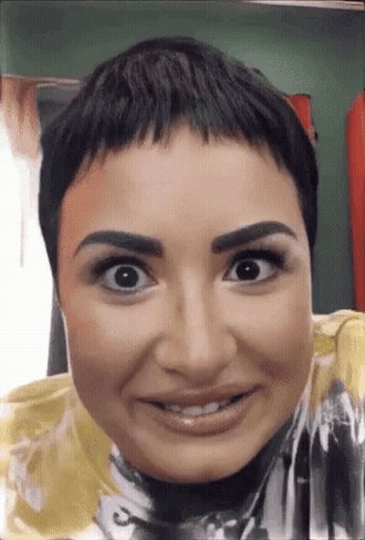A Close Up Of A Woman 'S Face With A Very Short Haircut . GIF