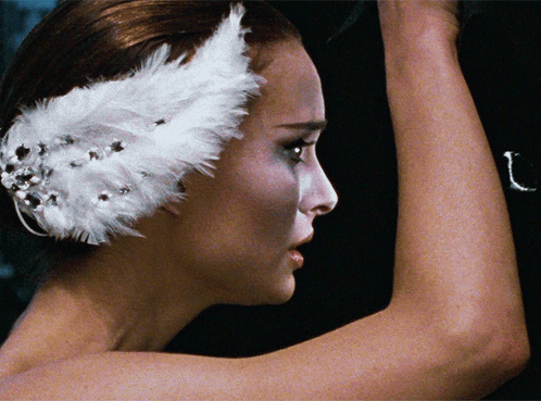A Close Up Of A Woman 'S Face With A White Feather On Her Head GIF