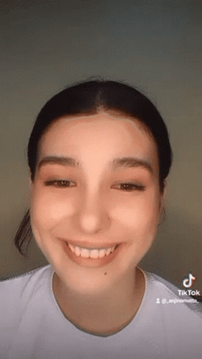 A Close Up Of A Woman 'S Face With A White Shirt On Smiling . GIF