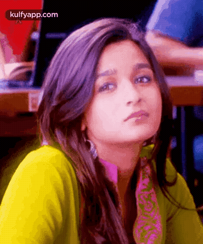 A Close Up Of A Woman 'S Face With A Yellow Shirt And A Pink Scarf . GIF