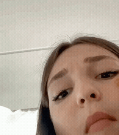 A Close Up Of A Woman 'S Face With A Yellow Sticker On Her Nose . GIF