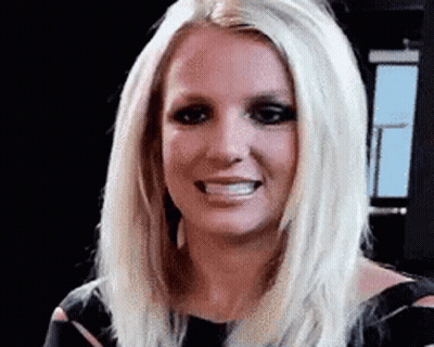 A Close Up Of A Woman 'S Face With Blonde Hair And A Black Dress . GIF