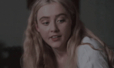 A Close Up Of A Woman 'S Face With Blonde Hair And A White Shirt . GIF