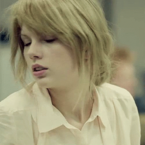A Close Up Of A Woman 'S Face With Blonde Hair And A White Shirt GIF