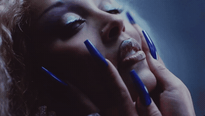 A Close Up Of A Woman 'S Face With Blue Long Nails GIF