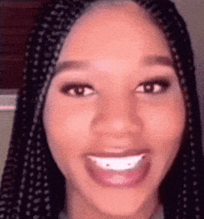 A Close Up Of A Woman 'S Face With Braids And A Big Smile . GIF