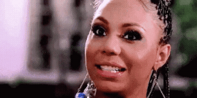 A Close Up Of A Woman 'S Face With Braids And Earrings Smiling . GIF