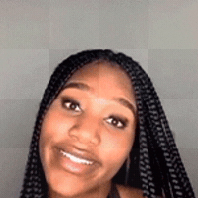 A Close Up Of A Woman 'S Face With Braids Smiling . GIF
