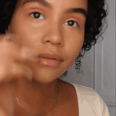 A Close Up Of A Woman 'S Face With Curly Hair And A White Shirt . GIF