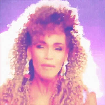 A Close Up Of A Woman 'S Face With Curly Hair And Earrings GIF