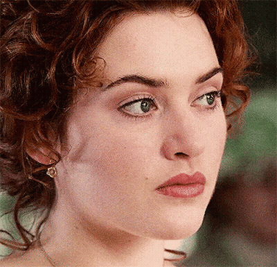 A Close Up Of A Woman 'S Face With Curly Hair And Green Eyes GIF