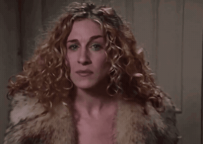 A Close Up Of A Woman 'S Face With Curly Hair Wearing A Fur Coat . GIF
