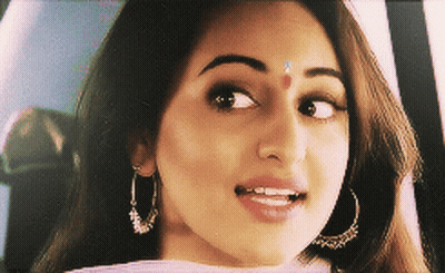 A Close Up Of A Woman 'S Face With Earrings And A Red Dot On Her Forehead GIF