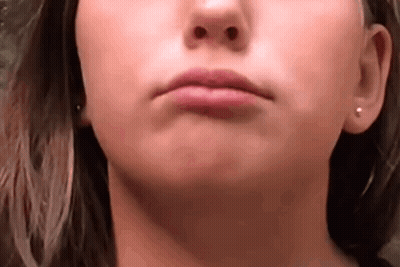 A Close Up Of A Woman 'S Face With Earrings On Her Ears . GIF