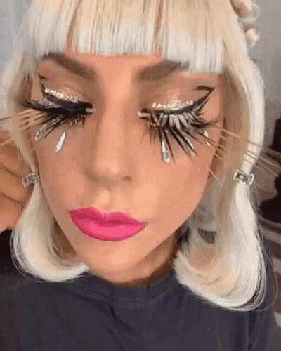A Close Up Of A Woman 'S Face With Feathered Eyelashes And Pink Lips GIF