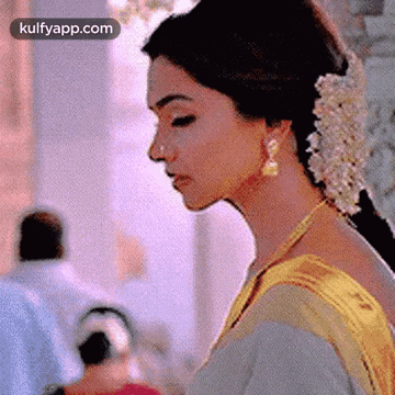 A Close Up Of A Woman 'S Face With Flowers In Her Hair And Earrings . GIF
