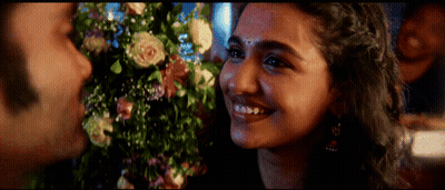 A Close Up Of A Woman 'S Face With Flowers In The Background GIF