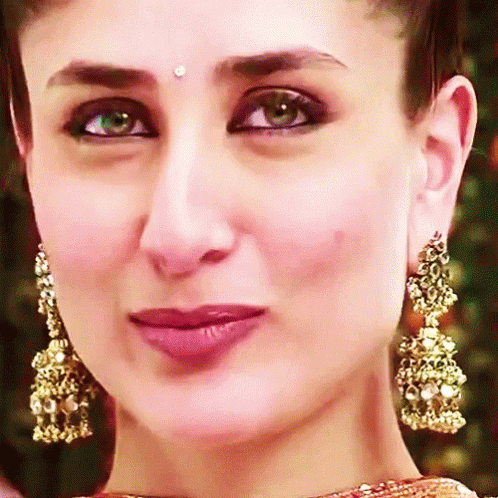 A Close Up Of A Woman 'S Face With Gold Earrings GIF
