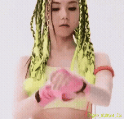 A Close Up Of A Woman 'S Face With Green And Yellow Braids And A Pink Background GIF