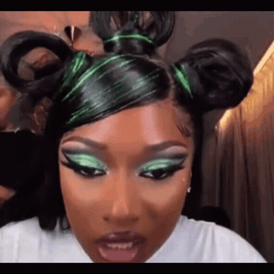 A Close Up Of A Woman 'S Face With Green Eye Shadow And A Bun In Her Hair . GIF