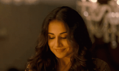 A Close Up Of A Woman 'S Face With Her Eyes Closed And A Chandelier In The Background . GIF