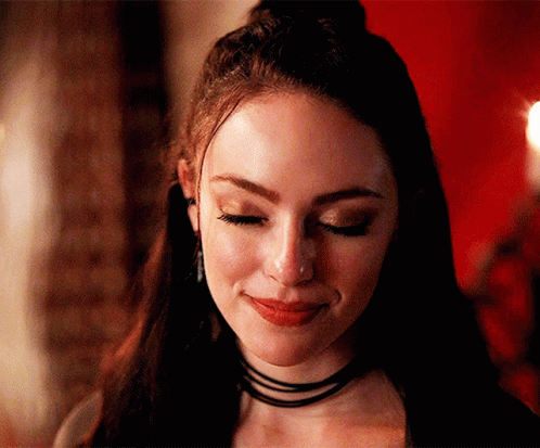 A Close Up Of A Woman 'S Face With Her Eyes Closed And A Choker On Her Neck . GIF