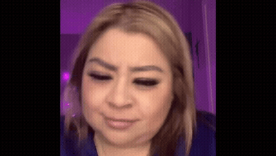 A Close Up Of A Woman 'S Face With Her Eyes Closed And A Purple Background . GIF