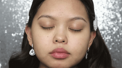 A Close Up Of A Woman 'S Face With Her Eyes Closed And Earrings GIF