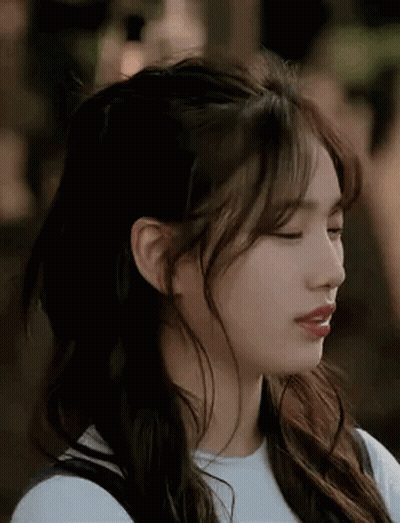 A Close Up Of A Woman 'S Face With Her Eyes Closed And Her Hair In A Half Up Half Down Hairstyle . GIF
