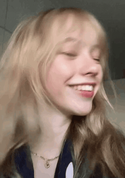 A Close Up Of A Woman 'S Face With Her Eyes Closed And Smiling . GIF