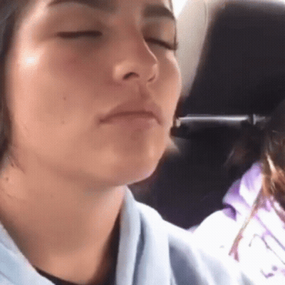 A Close Up Of A Woman 'S Face With Her Eyes Closed In A Car GIF