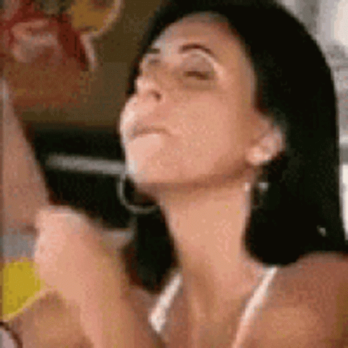 A Close Up Of A Woman 'S Face With Her Eyes Closed . She Is Wearing Hoop Earrings And A Bikini Top . GIF