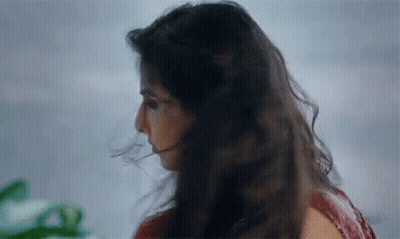 A Close Up Of A Woman 'S Face With Her Hair Blowing In The Wind GIF