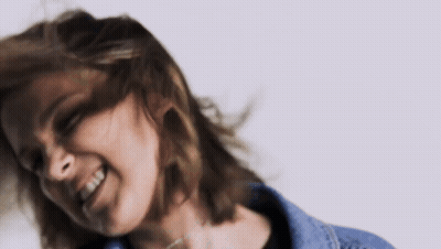 A Close Up Of A Woman 'S Face With Her Hair Blowing In The Wind . GIF