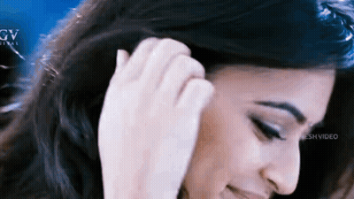 A Close Up Of A Woman 'S Face With Her Hand In Her Hair . GIF