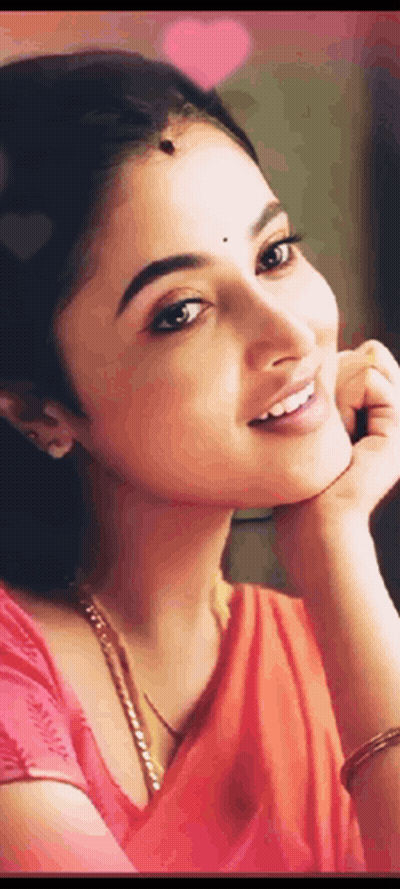 A Close Up Of A Woman 'S Face With Her Hand On Her Chin . She Is Wearing A Red Saree And Smiling . GIF